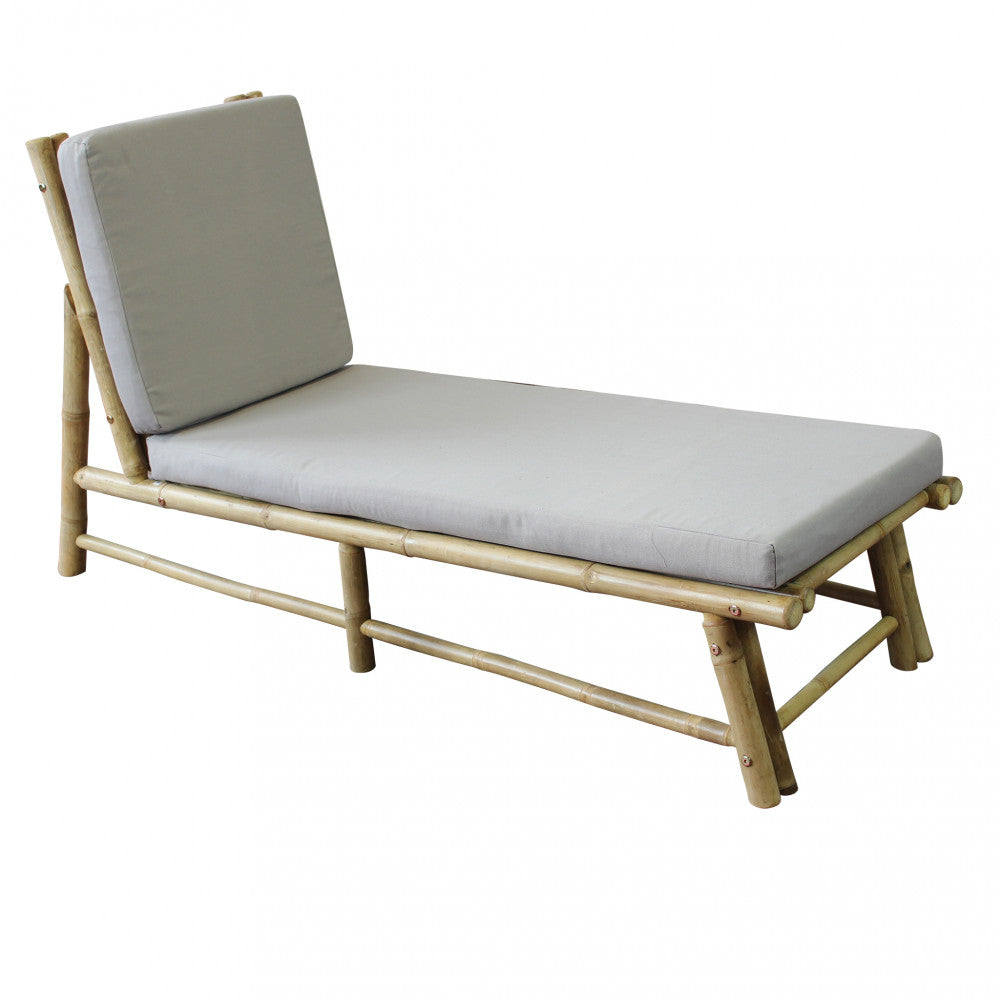 Lettino prendisole Blue Lagoon in legno e bamboo, di colore marrone, posizionato in un giardino lussureggiante.