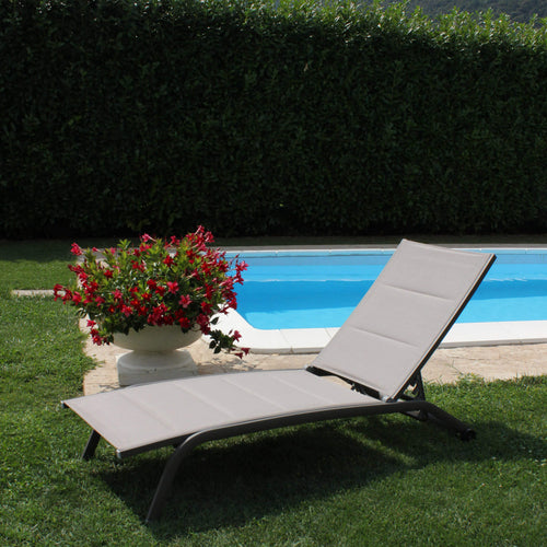 Lettino prendisole Itaca impilabile di colore taupe con struttura in alluminio, posizionato a bordo piscina.