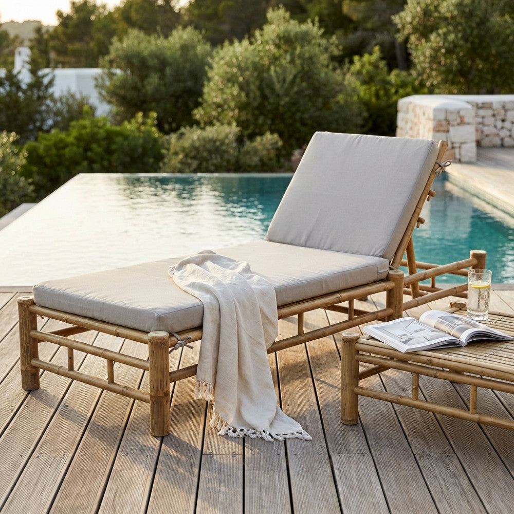 Lettino prendisole RONIK in legno marrone con cuscino sfoderabile, posizionato a bordo piscina su una terrazza in legno.