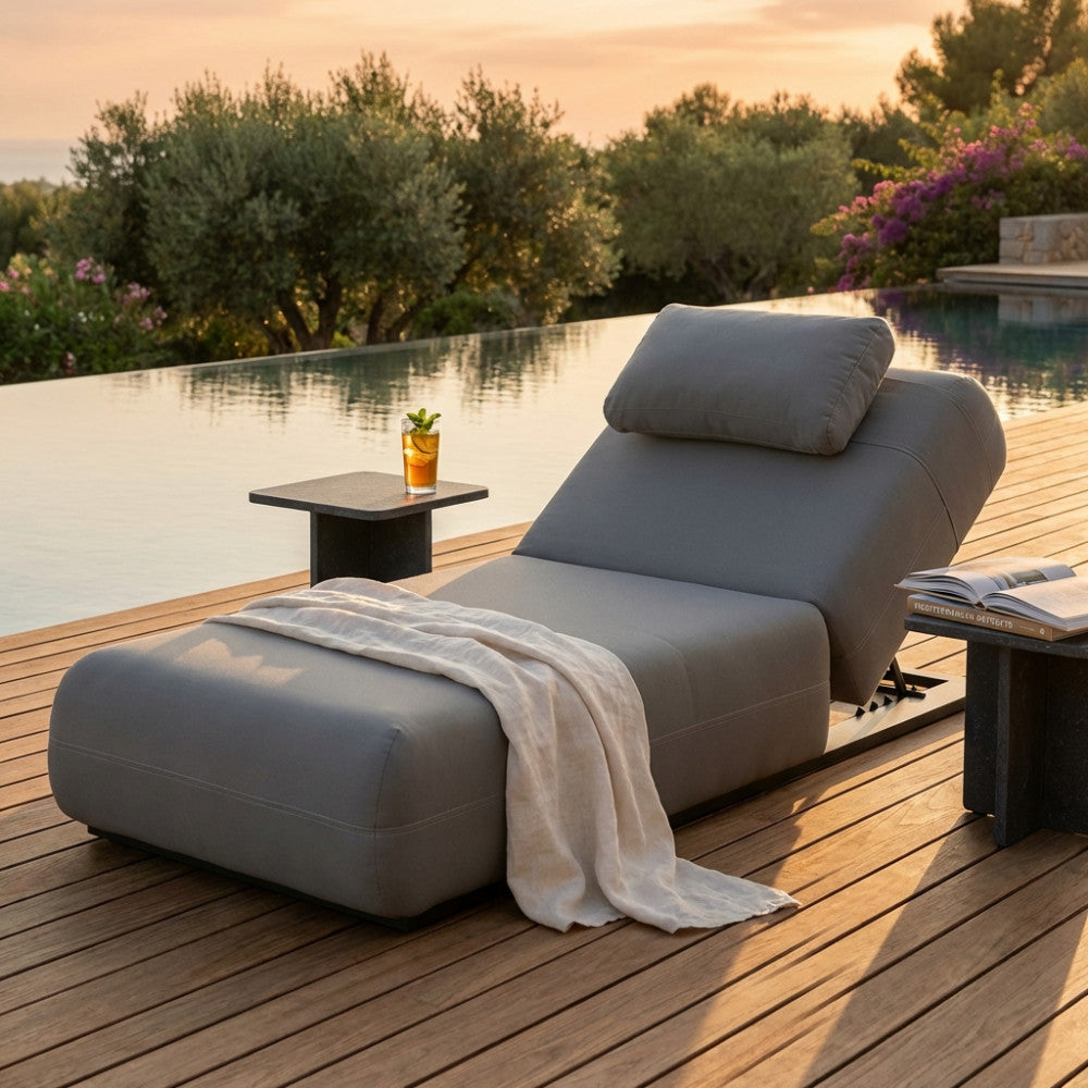 Lettino prendisole Tucumã in alluminio grigio scuro a bordo piscina al tramonto.