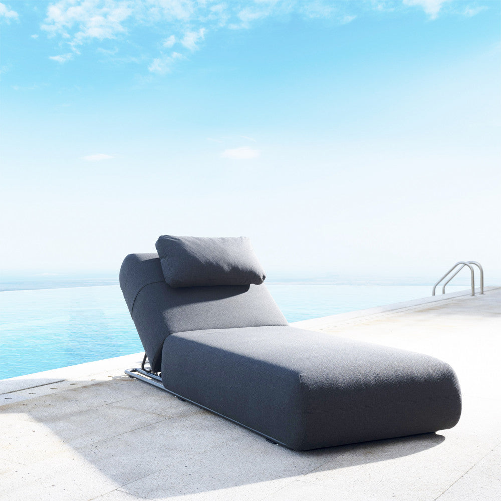 Lettino outdoor Tucumã posizionato su una terrazza in pietra chiara vista mare.