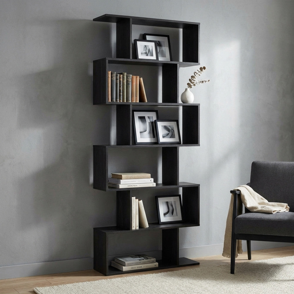 Libreria geometrica antracite allestita in un salotto moderno con poltrona grigia e cornici decorative.