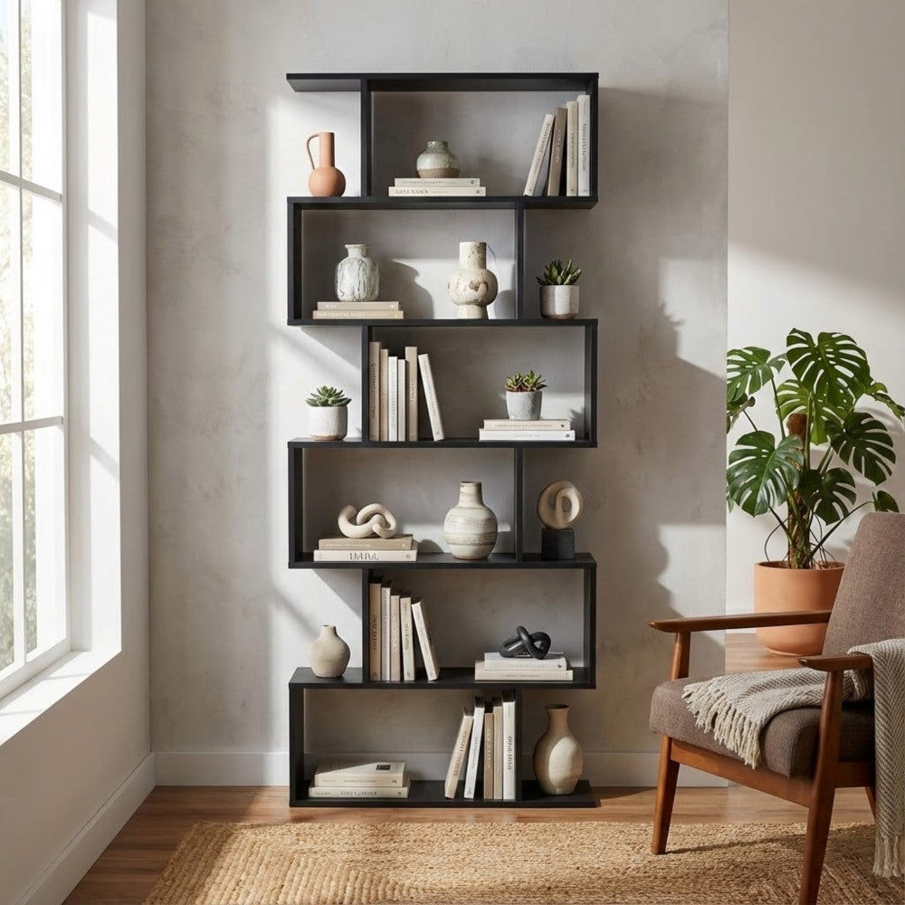 Libreria di design antracite decorata con piante, vasi in ceramica e libri, vicino a una sedia in tessuto marrone.