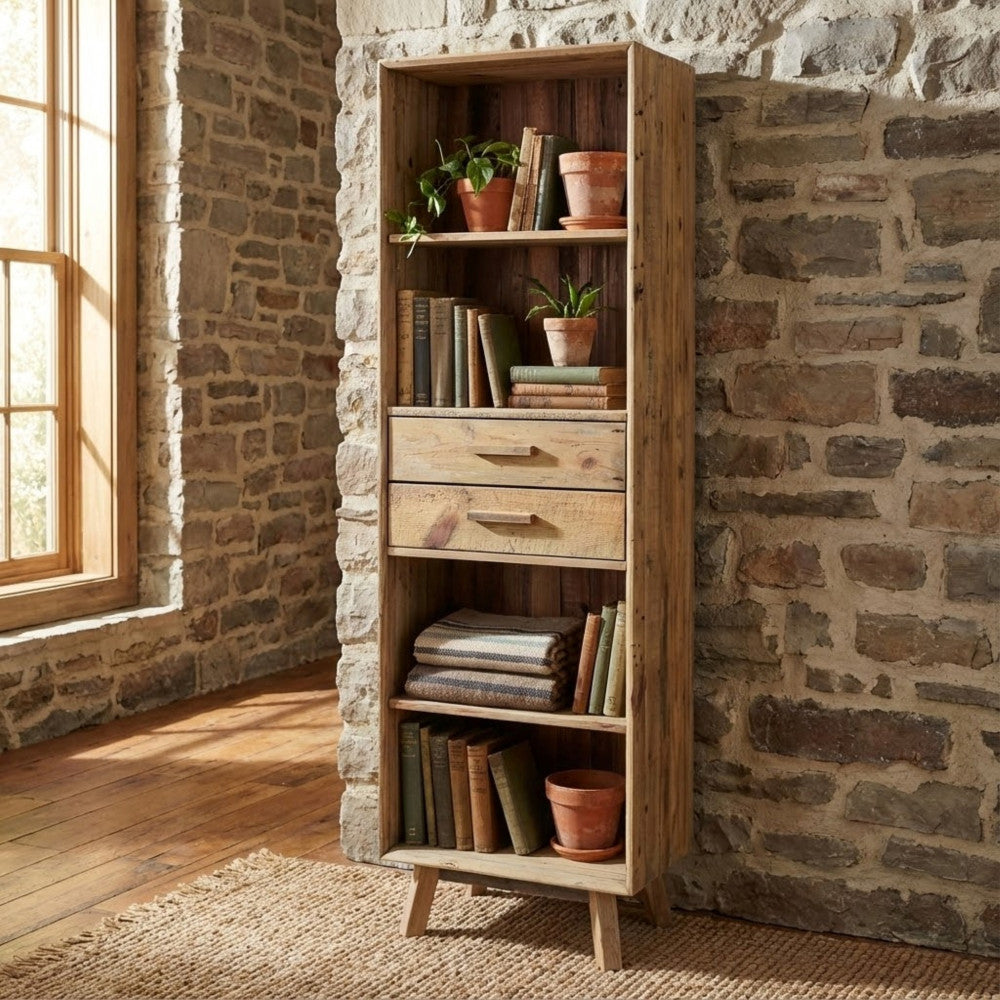 Libreria Collin allestita con libri e coperte, posizionata contro una parete in pietra naturale per un contrasto materico.