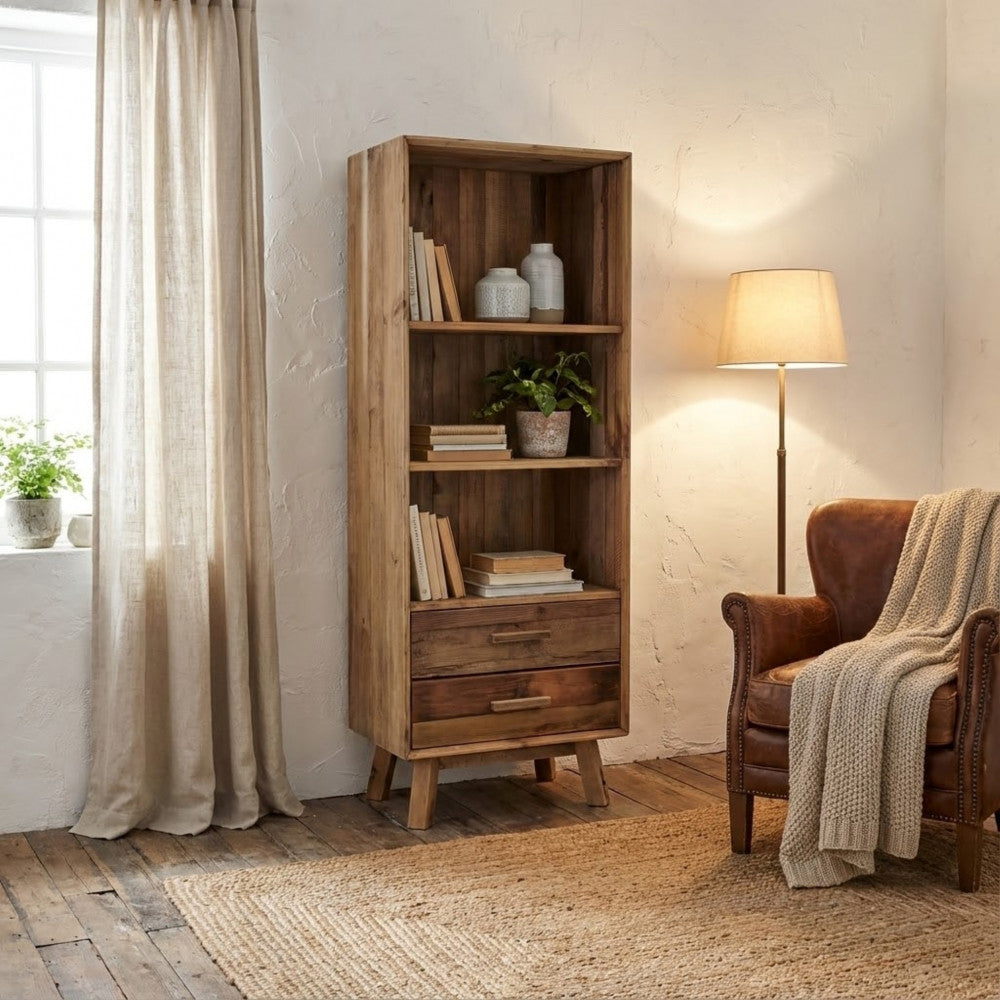 Libreria Justin inserita in un angolo lettura serale con lampada da terra, poltrona in pelle e tendaggi in lino.