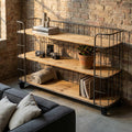 Libreria ABNER in acciaio antracite e legno marrone, ambientata in un salotto dal design industriale con pareti in mattoni a vista e decorazioni vintage.
