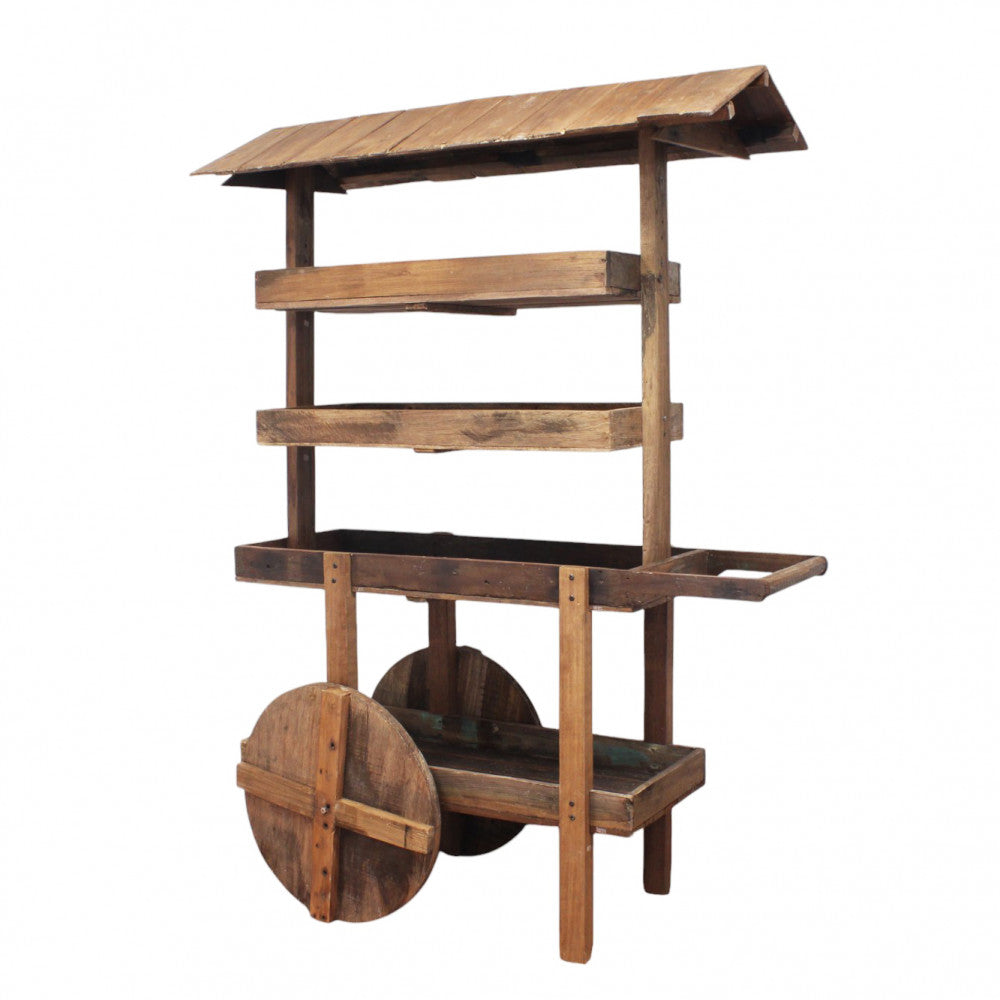 Vista frontale del carrello MOBILE ALFRED in legno marrone con tetto spiovente e ruote decorative.