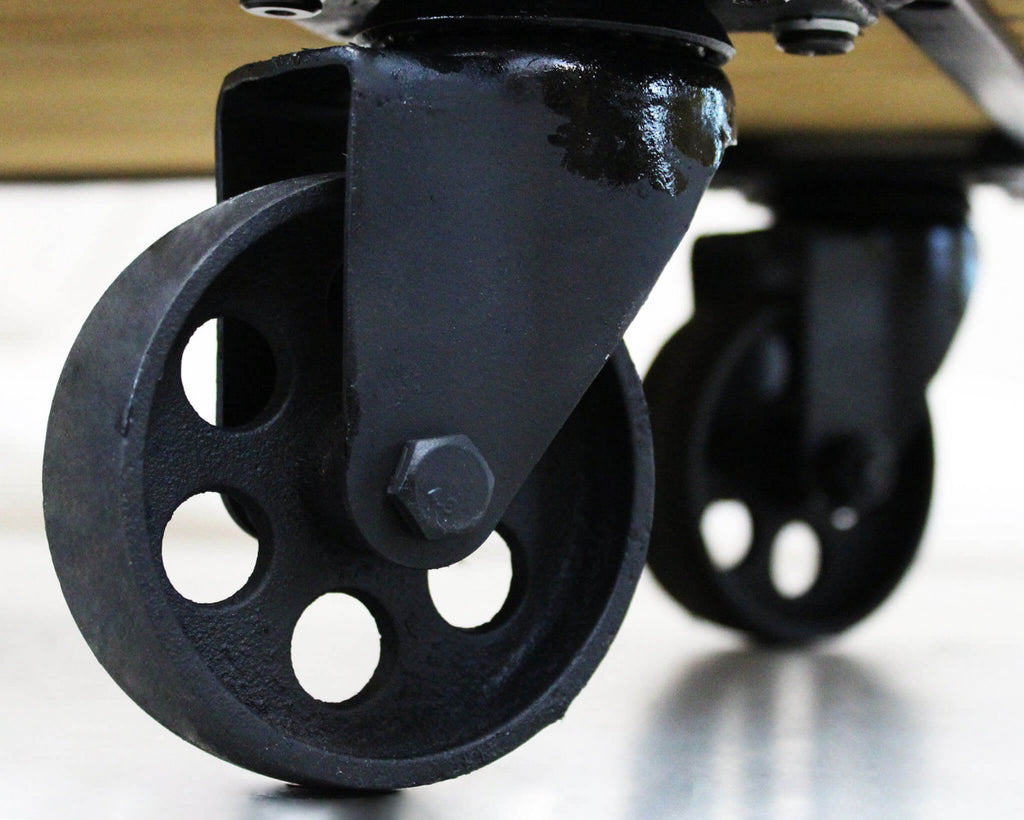 Dettaglio ravvicinato delle robuste ruote in metallo nero del carrello industriale.