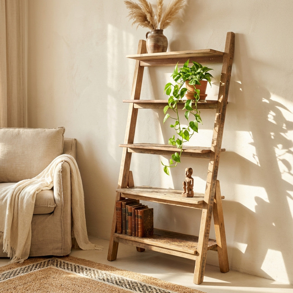 Immagine ambientata della libreria a scala Anthony in legno riciclato in una stanza soleggiata, decorata con una pianta di pothos cadente, libri vintage e una piccola scultura in legno.