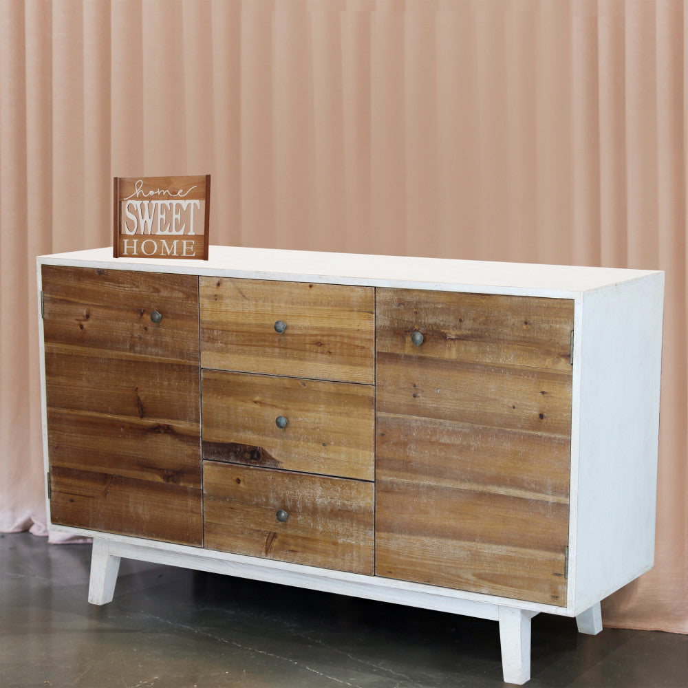 Credenza Austen ambientata in uno spazio espositivo con tendaggio rosa cipria sullo sfondo e targa decorativa in legno.