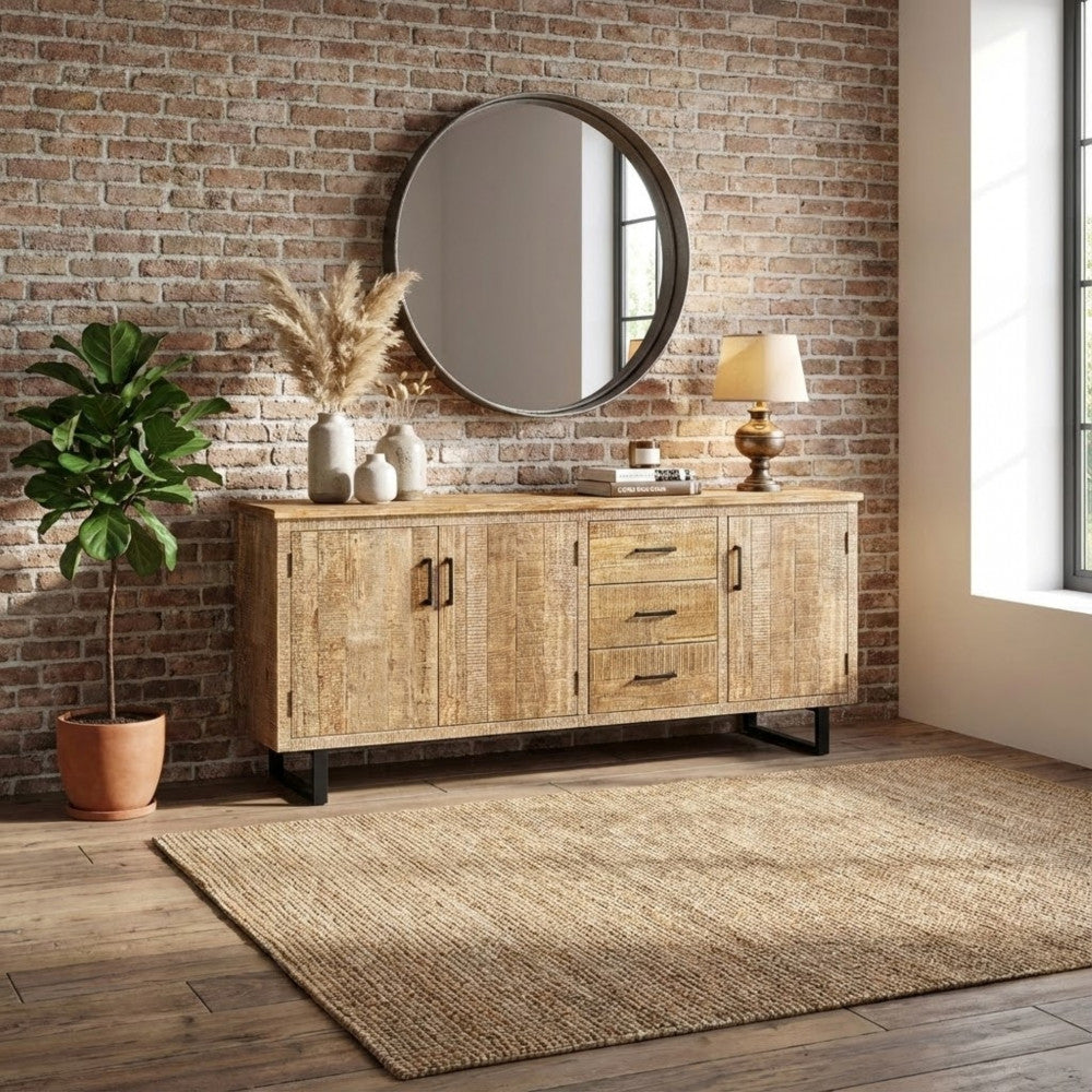 Credenza Barret inserita in un contesto industriale con parete in mattoni a vista, specchio rotondo e pianta d'appartamento.