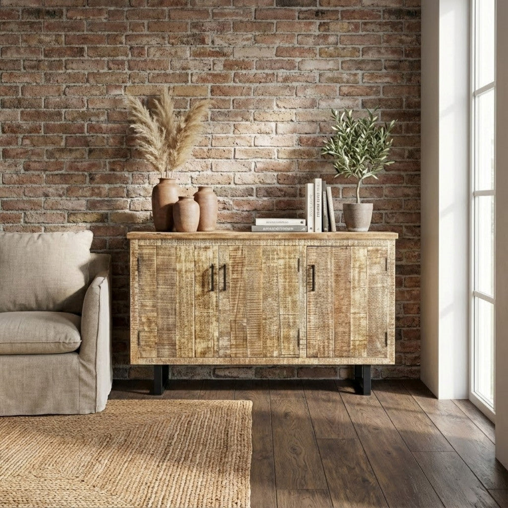 Credenza Benson ambientata contro una parete in mattoni a vista, arricchita da vasi in terracotta e pampas.