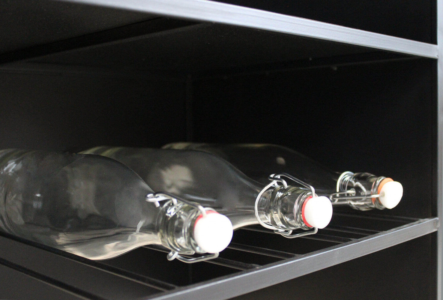 Dettaglio dei ripiani inferiori in metallo a doghe, progettati per ospitare in sicurezza le bottiglie di vino.