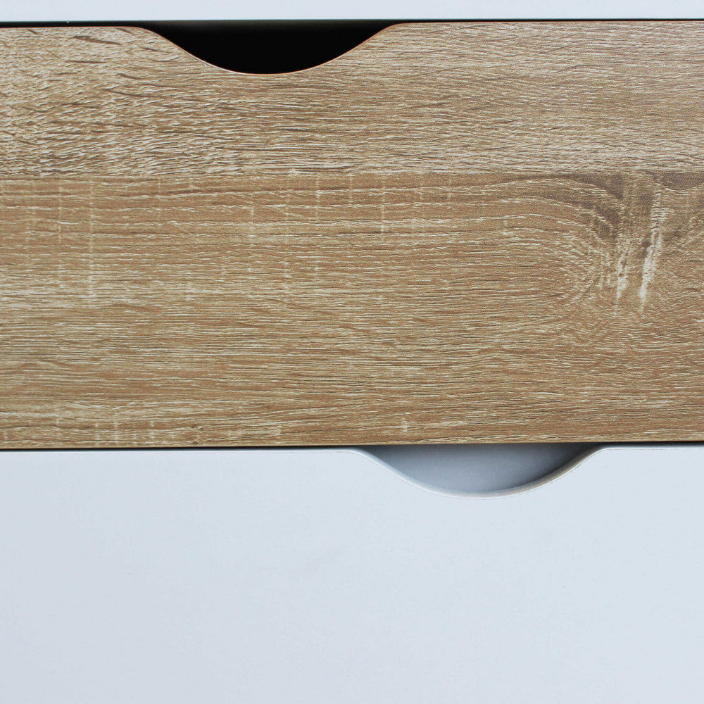 Dettaglio frontale della venatura del legno sul cassetto superiore, in contrasto con il bianco liscio sottostante.