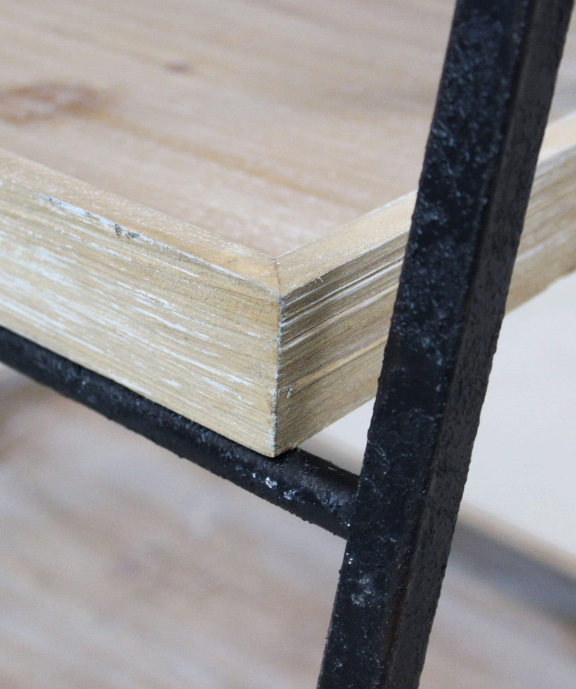 Primo piano del ripiano in legno materico appoggiato sulla struttura in metallo martellato.