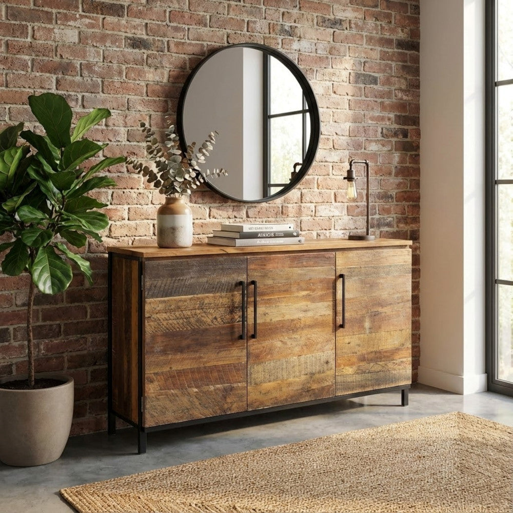 Credenza BRAM posizionata contro un muro di mattoni a vista con specchio rotondo superiore.