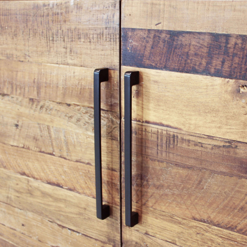 Dettaglio ravvicinato delle maniglie in metallo nero opaco e della texture materica del legno sulla credenza BRAXTON.