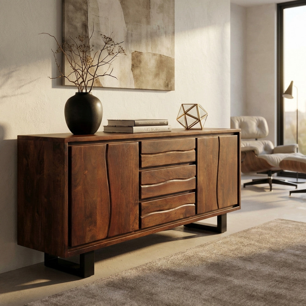 Vista angolata della credenza in acacia marrone in una stanza soleggiata, che mostra i frontali ondulati dei cassetti e le solide gambe in metallo.