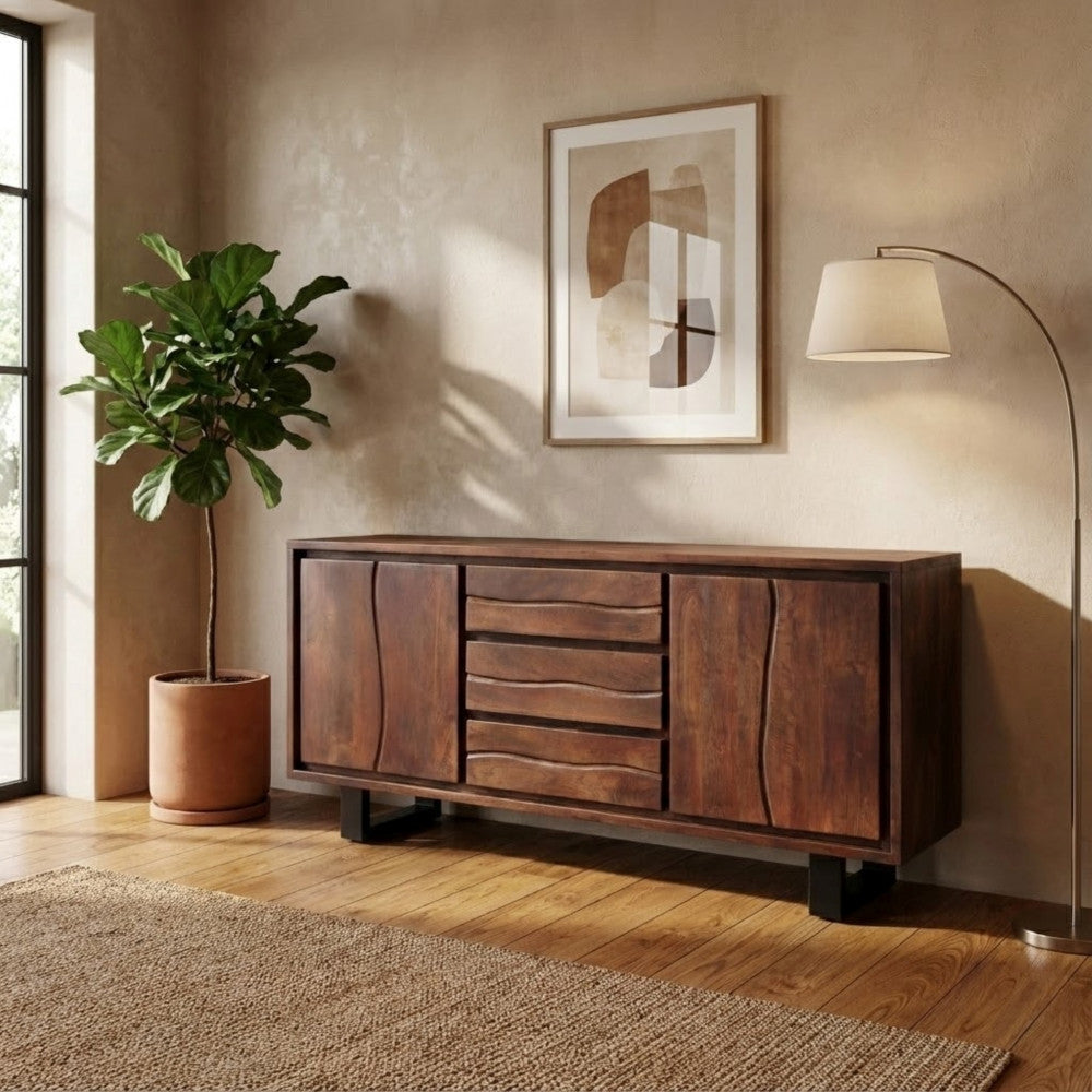 Ambientazione lifestyle della credenza in acacia abbinata a una pianta da interni alta e a una moderna lampada da terra.
