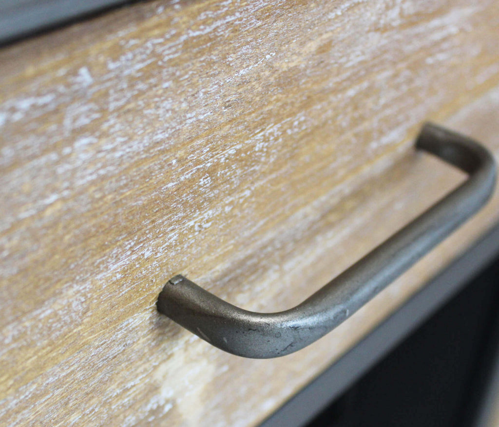 Primo piano della maniglia in metallo su cassetto in legno marrone con finitura rustica e venature a vista.