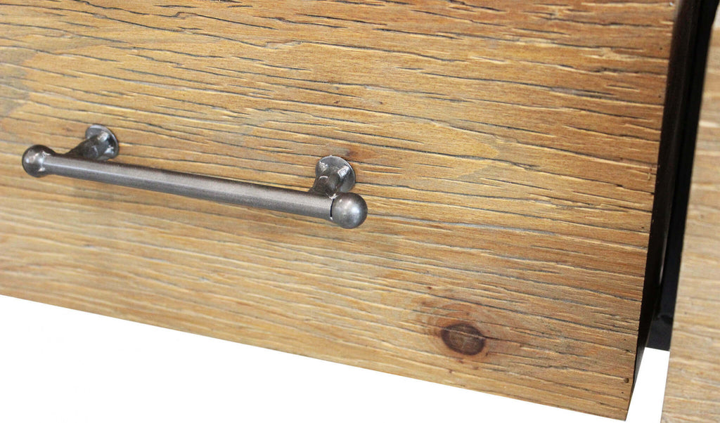 Primo piano della maniglia tubolare in metallo scuro applicata sul frontale in legno rustico del cassetto.