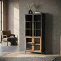 Vetrina Derby in legno e metallo nero ambientata in un soggiorno minimalista con poltrona in pelle.