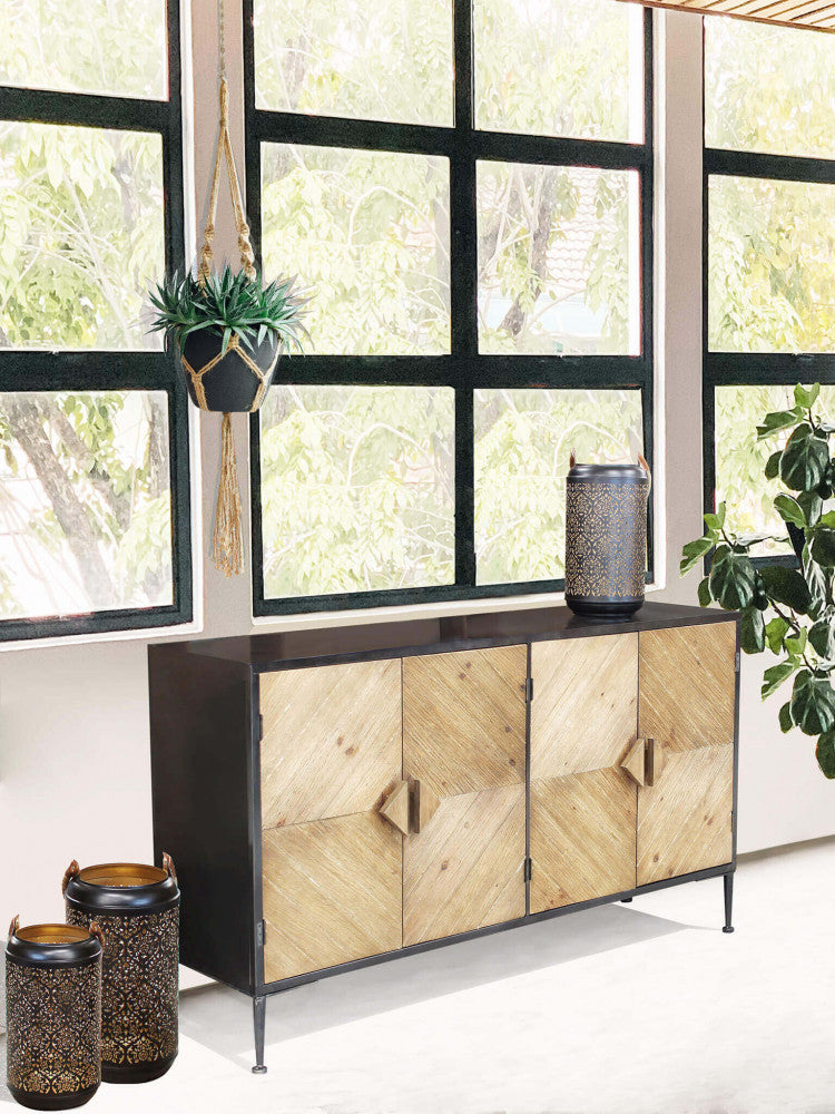 Credenza Derek posizionata in una veranda luminosa con ampie finestre, arricchita da piante sospese e lanterne in metallo scuro.