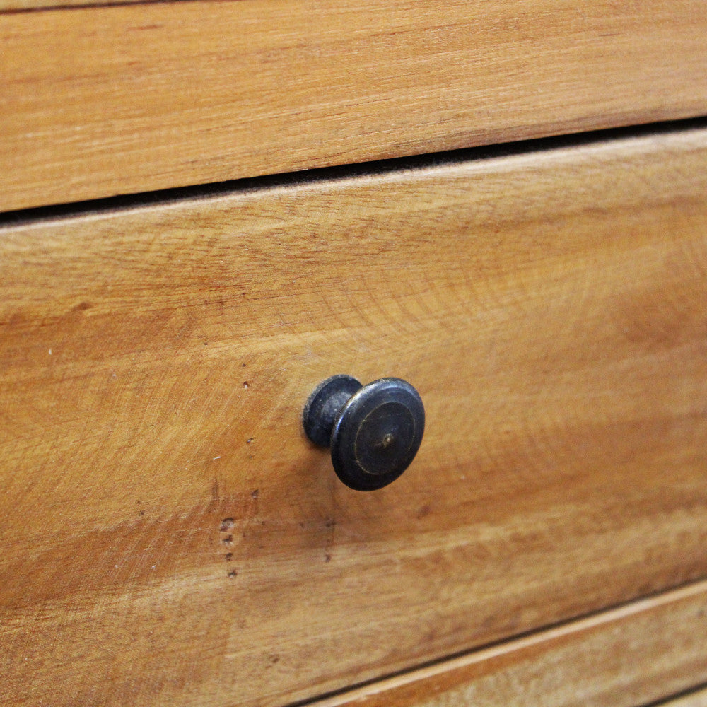 Dettaglio del pomello in metallo scuro sul cassetto in legno massello della libreria DEVEREUX.