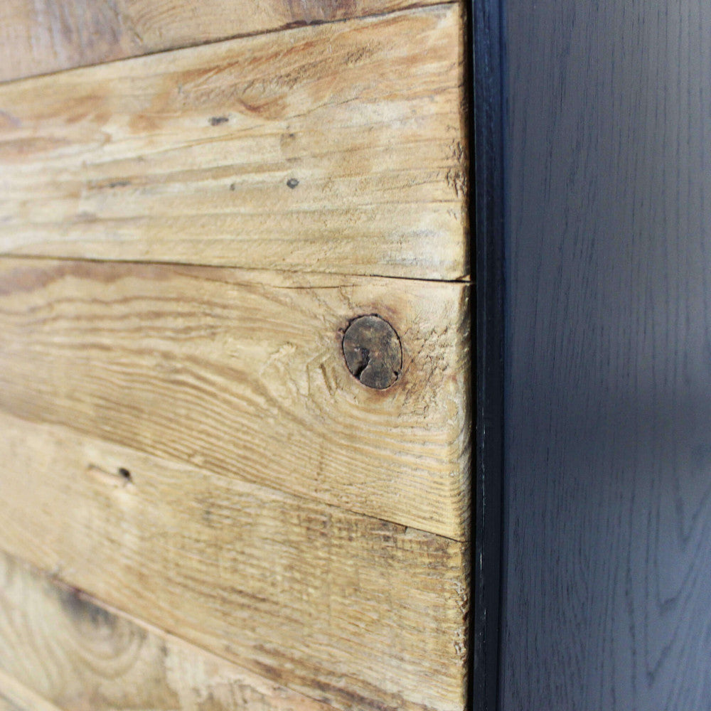 Primo piano della texture materica in pino riciclato e del profilo scuro della credenza Devin.