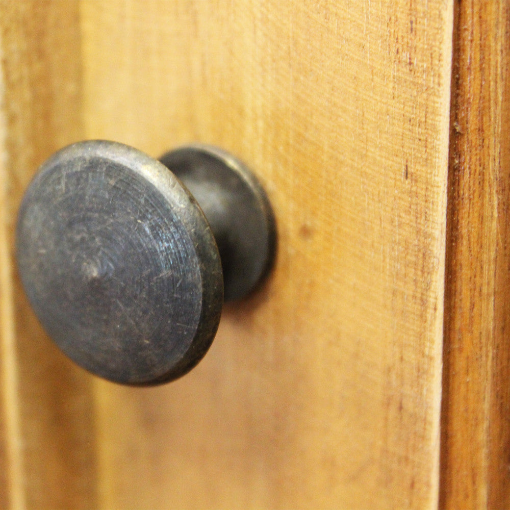 Dettaglio ravvicinato del pomello in metallo anticato sulla struttura in legno della vetrina.