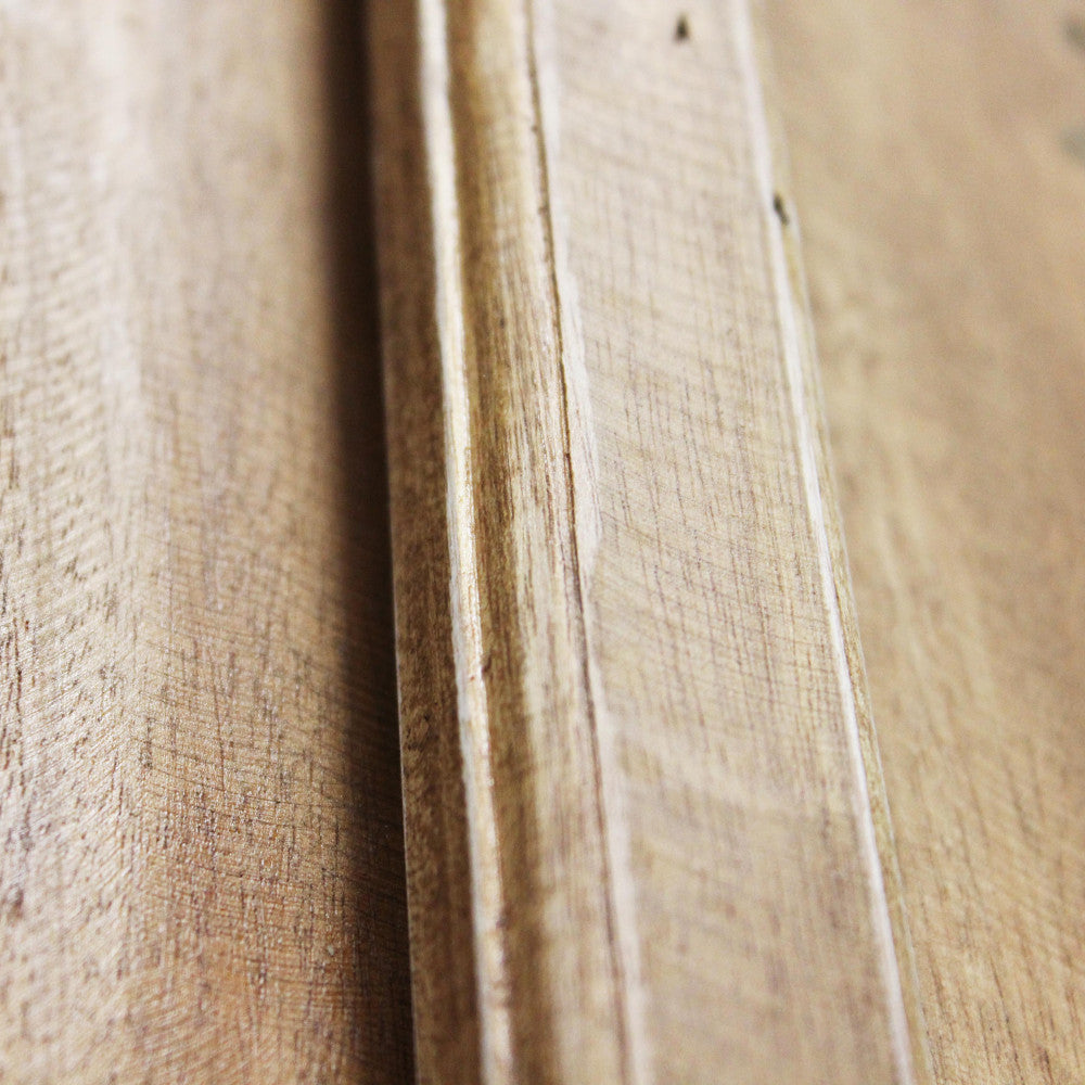 Particolare della modanatura in legno massello, che mostra la texture tattile del materiale.