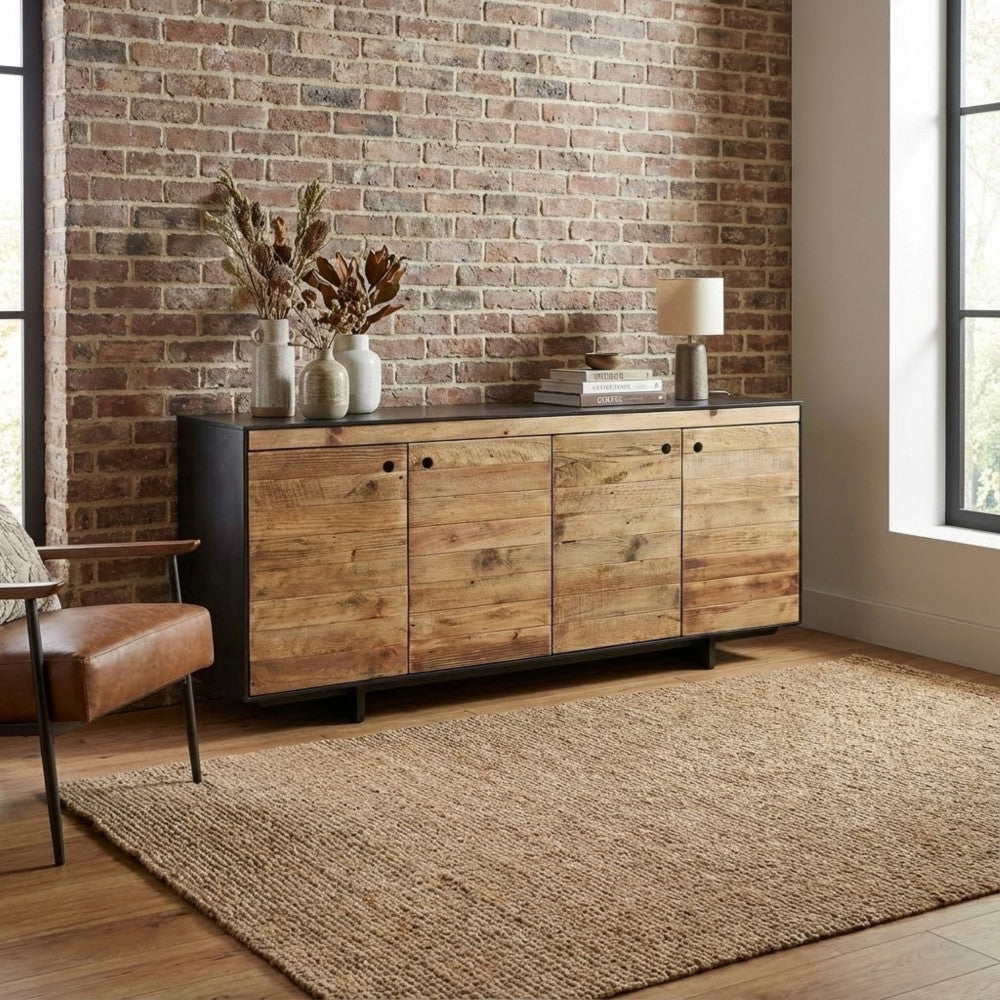 Credenza ELDRED ambientata contro una parete in mattoni a vista con tappeto in iuta.