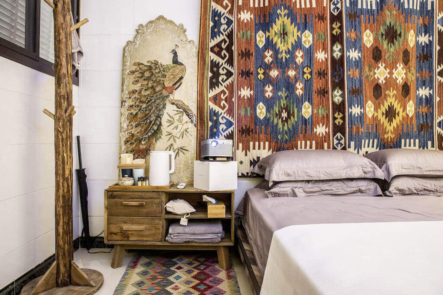 Ambientazione eclettica con il comodino ELSDON utilizzato come mobiletto accanto a un letto, decorato con arazzi e oggetti d'arte.