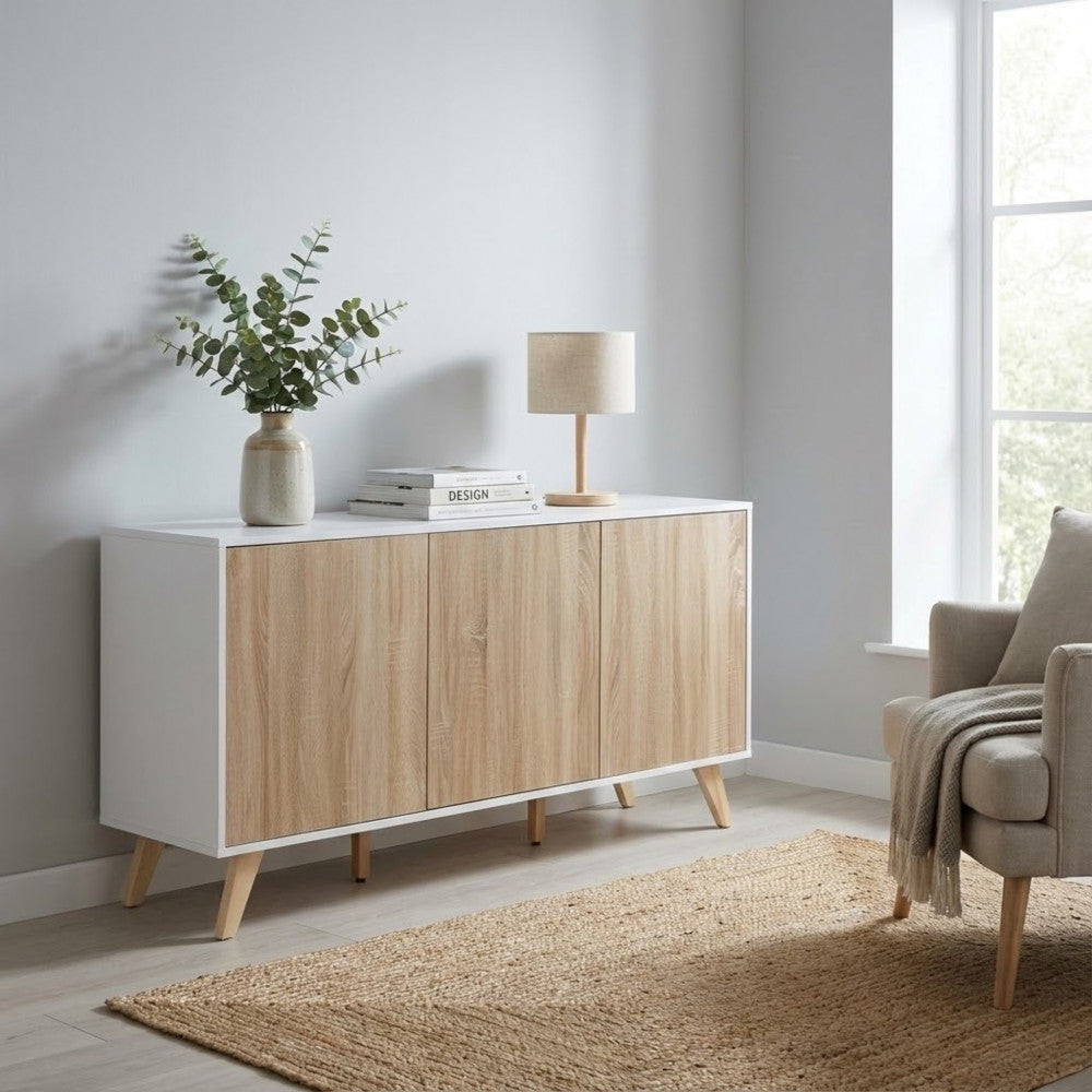 Ambientazione lifestyle della credenza in un salotto moderno, affiancata da una poltrona beige e un tappeto in iuta.