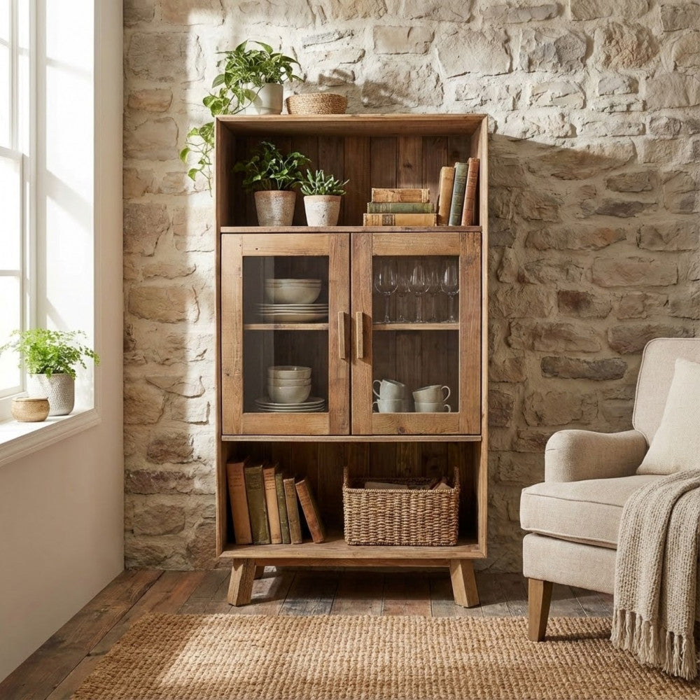 Credenza Elvin ambientata contro una parete in pietra naturale, affiancata da una poltrona beige.