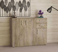 Credenza Flexi in rovere chiaro ambientata in un soggiorno luminoso con decorazioni da parete in metallo.
