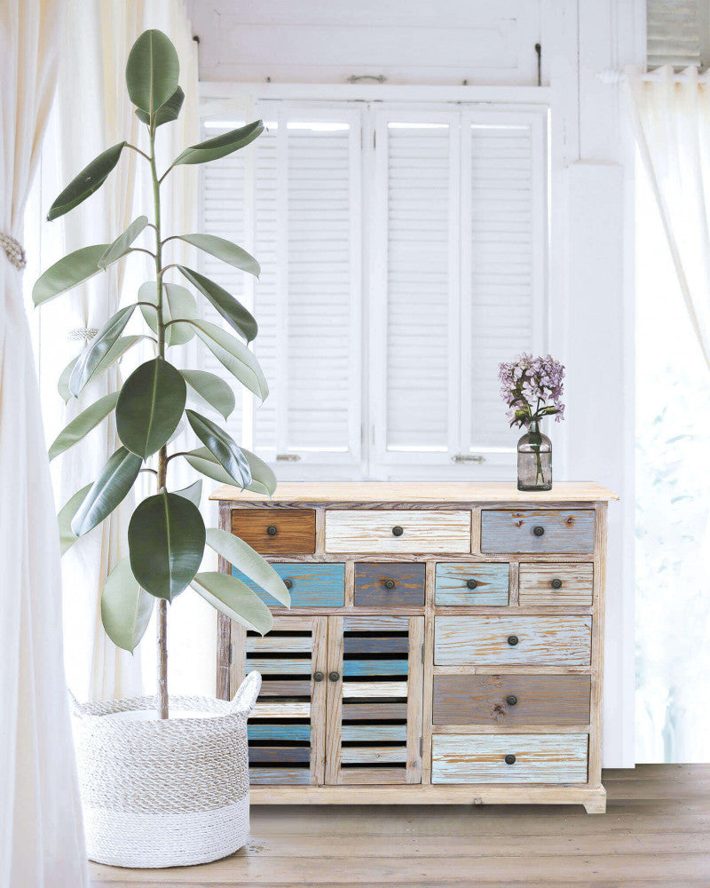 Credenza GREG inserita in un ambiente luminoso e moderno accanto a una grande pianta d'appartamento.