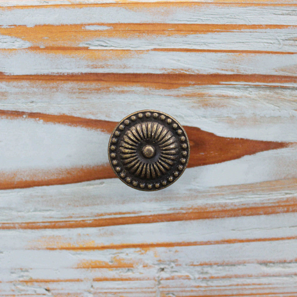 Dettaglio del pomello in metallo anticato su un cassetto in legno verniciato di azzurro.