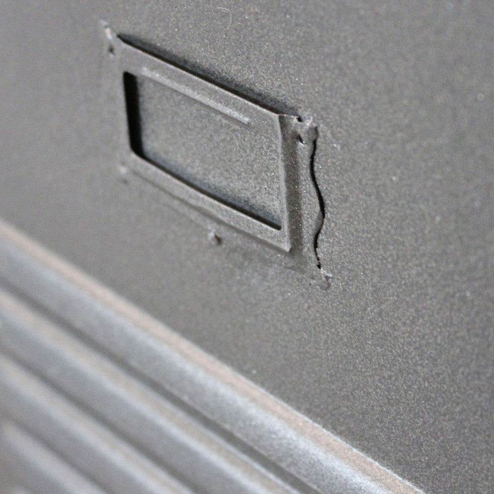 Dettaglio ravvicinato della maniglia e del porta etichetta in acciaio grigio sulla credenza Gabriel.