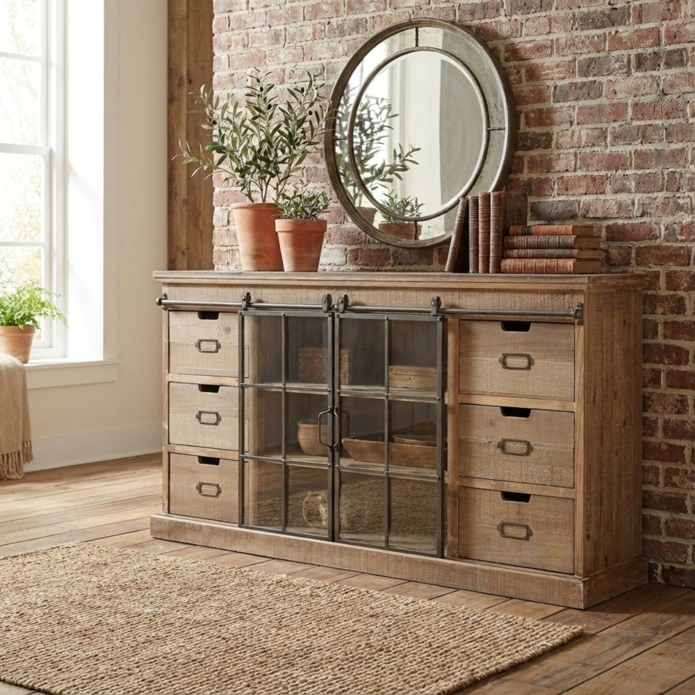 Credenza Gaston posizionata contro una parete in mattoni a vista, decorata con specchio rotondo e piante da interno.
