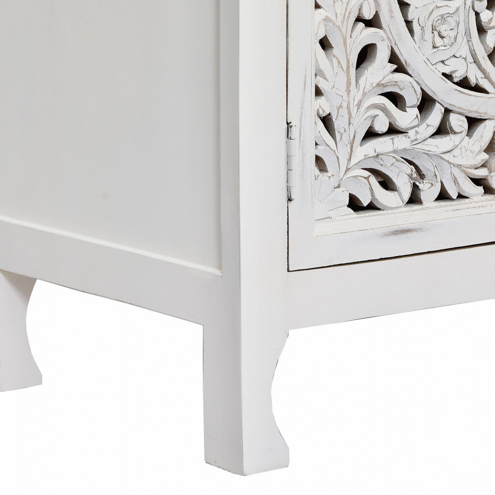 Dettaglio ravvicinato delle gambe in legno massello elegantemente rifinite e della cornice inferiore della credenza boho bianca.