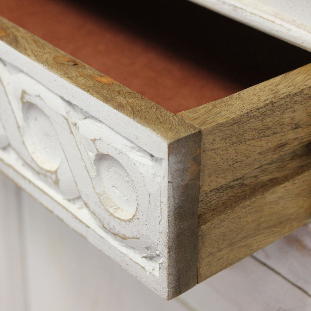 Primo piano di un cassetto aperto, che evidenzia la struttura in legno massello e il pannello frontale intagliato.