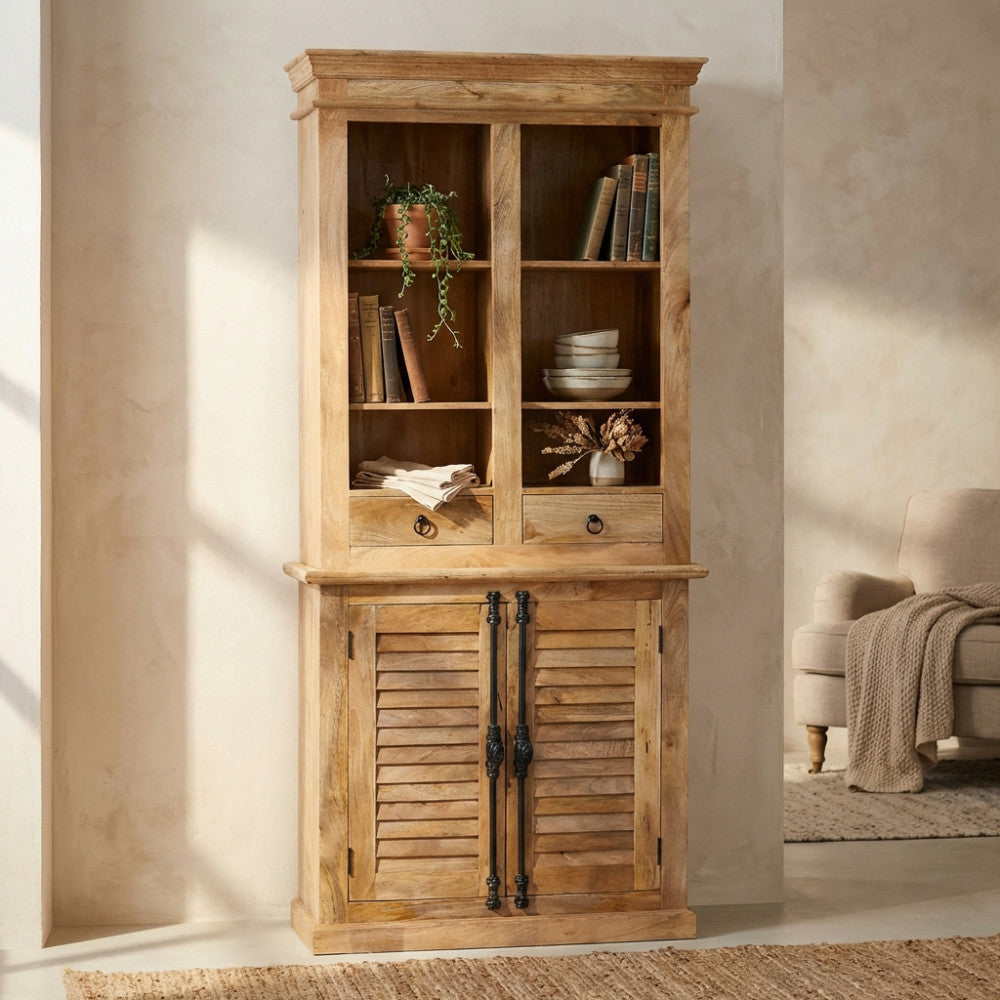 Credenza Julian in legno di mango chiaro, vista frontale in un salotto luminoso con poltrona neutra.