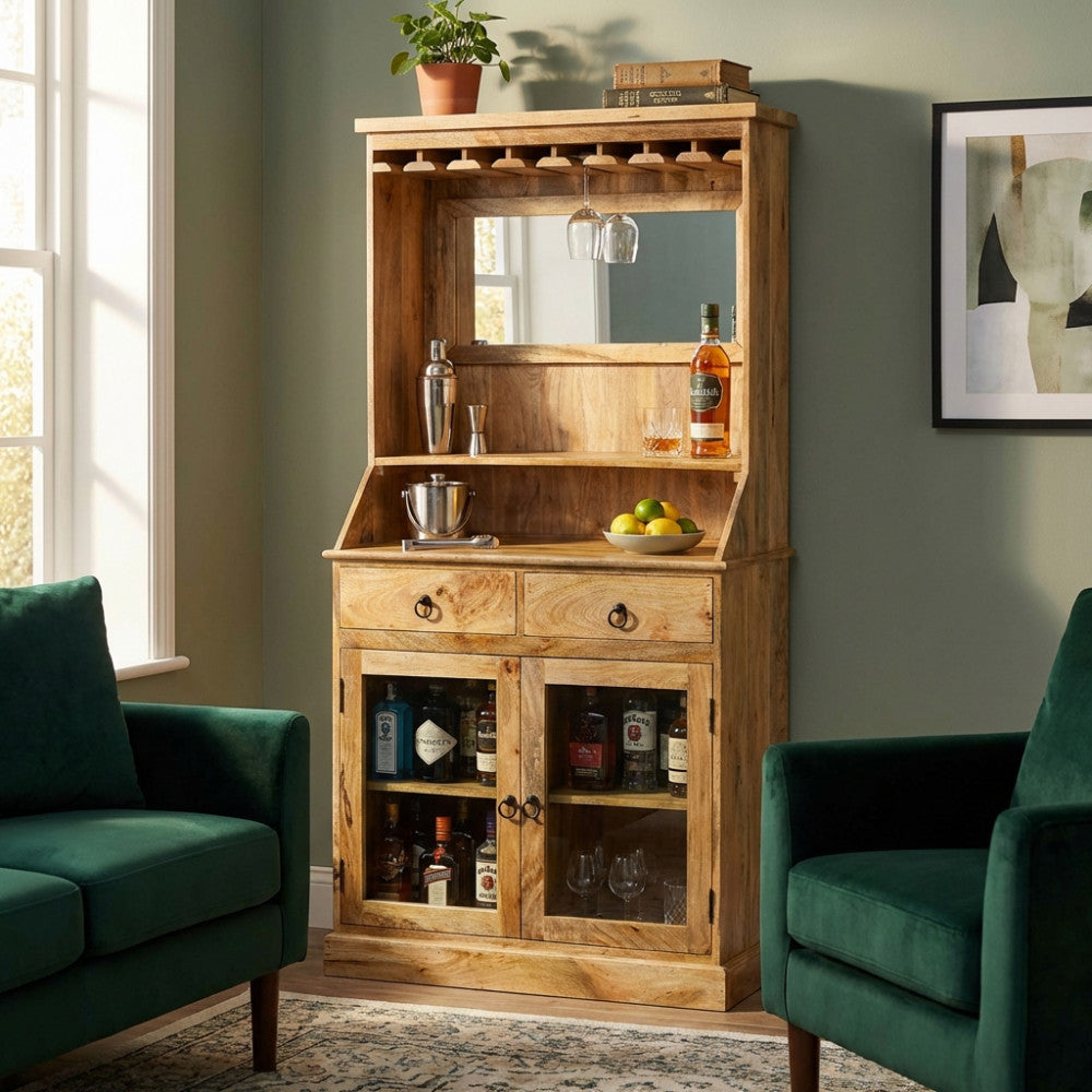 Mobile bar Lincoln in legno di mango ambientato in un salotto con poltrone in velluto verde.