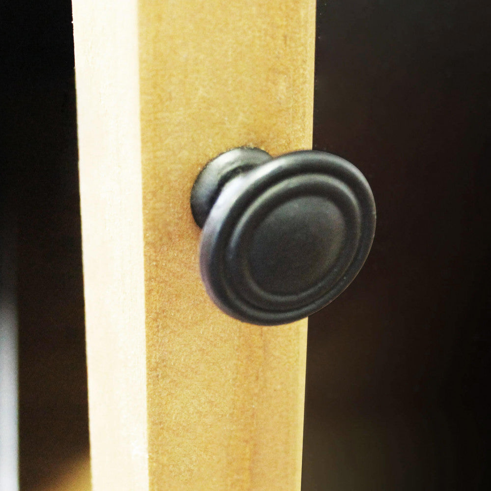 Dettaglio ravvicinato del pomello in metallo scuro sull'anta in legno del mobile.