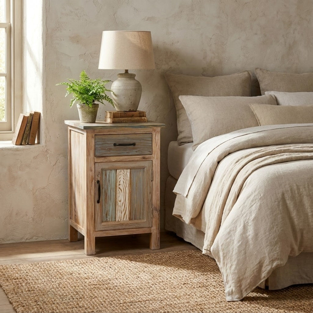 Comodino Reynold ambientato in una camera da letto dal design rustico, affiancato da una lampada in ceramica e piante decorative.