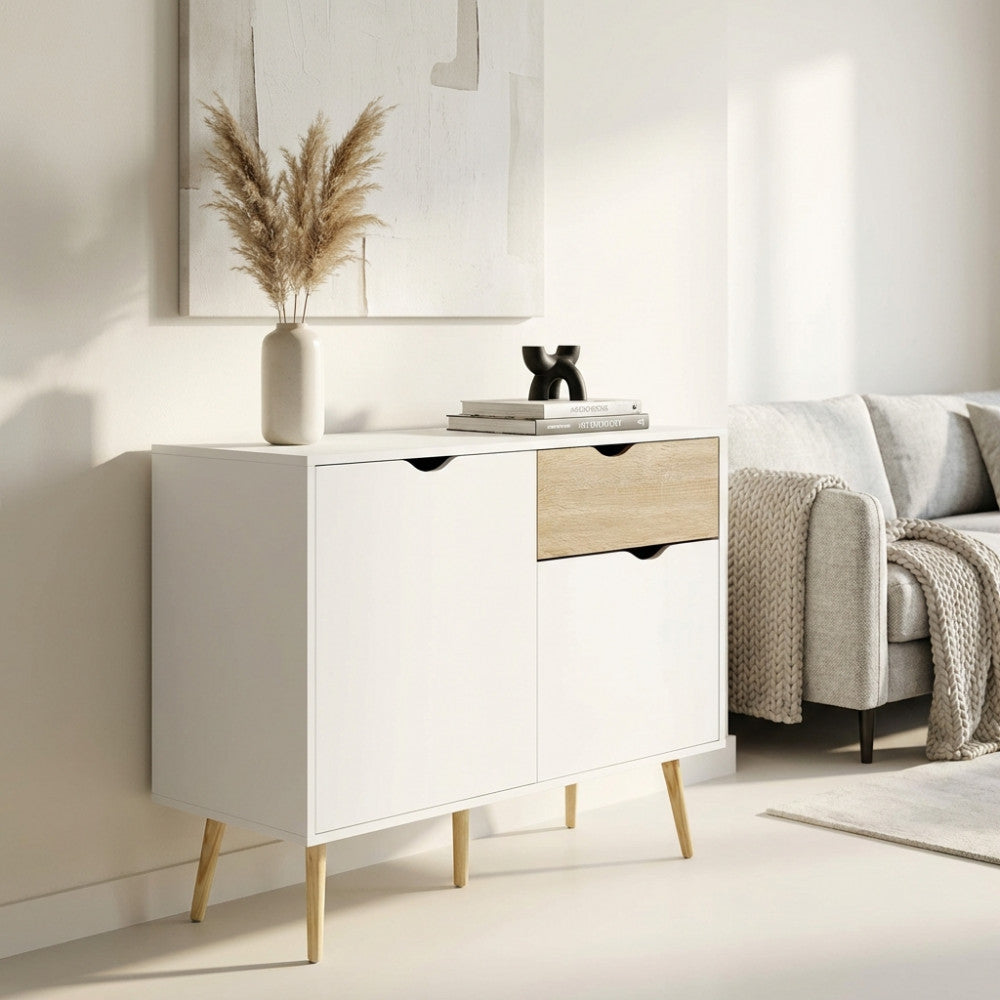 Vista angolare della credenza THEODORE inserita in un salotto elegante, affiancata da un divano grigio e decorazioni minimaliste.