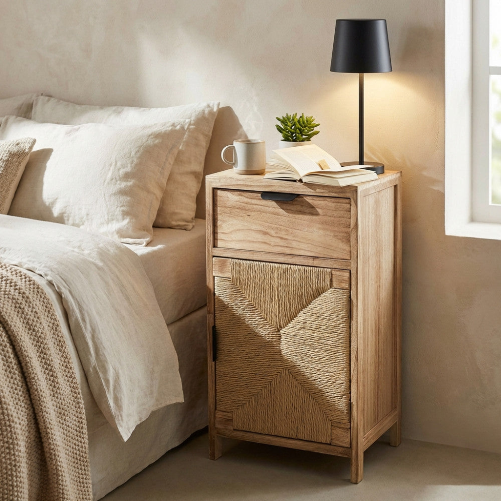 Mobiletto Carlos in legno di paulownia e corda posizionato come comodino accanto a un letto con lenzuola in lino chiaro.