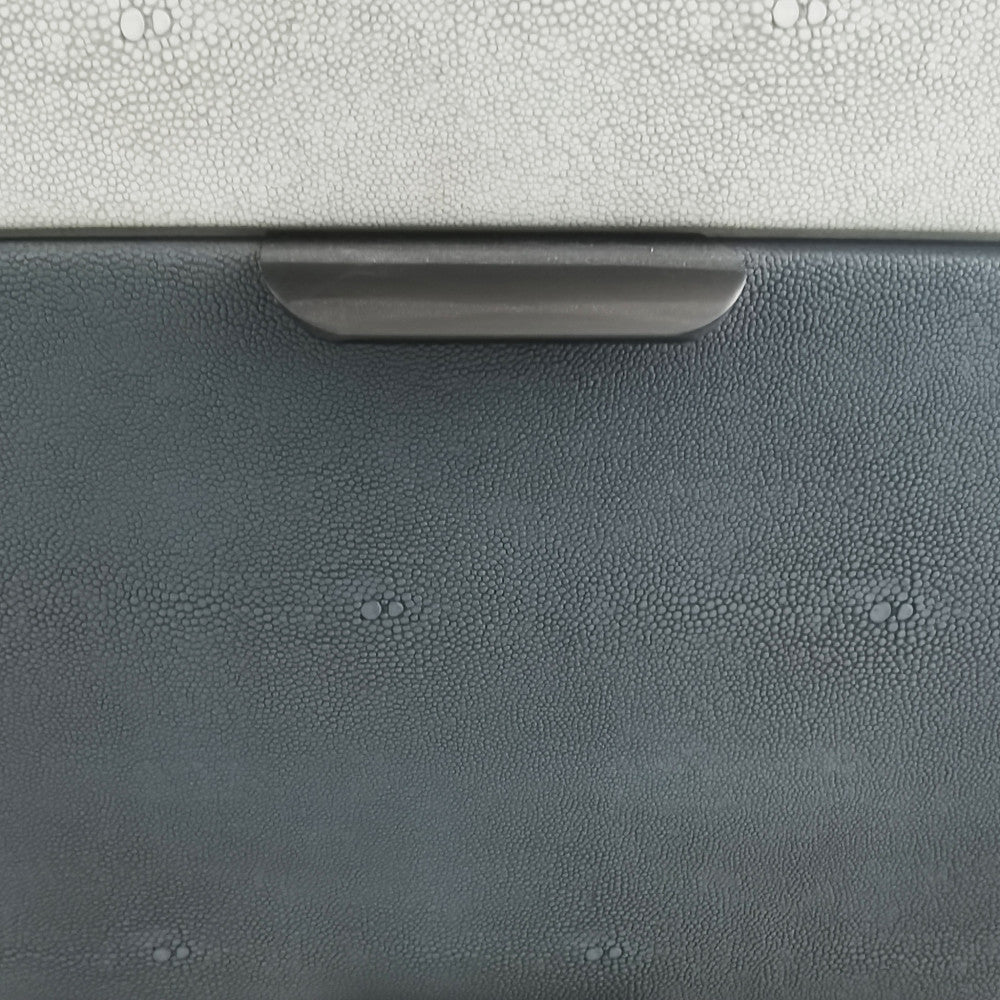 Primo piano della texture effetto galuchat dei cassetti e della maniglia minimalista in metallo scuro.