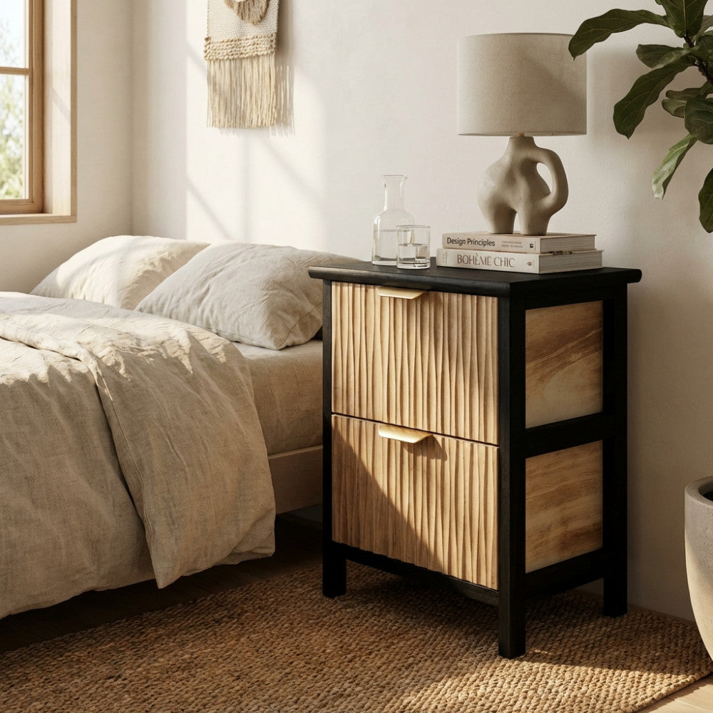 Dettaglio del comodino Cesar con cassetti scanalati, decorato con una lampada scultorea e libri di design in una camera da letto elegante.